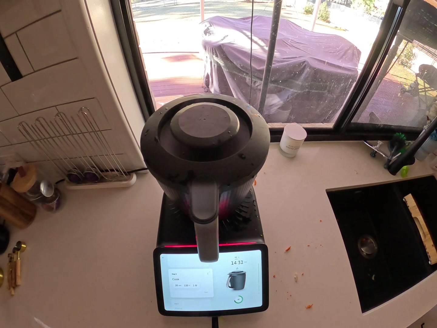 The Thermomix TM7 cooking on its own with the yard visible through the window behind it.